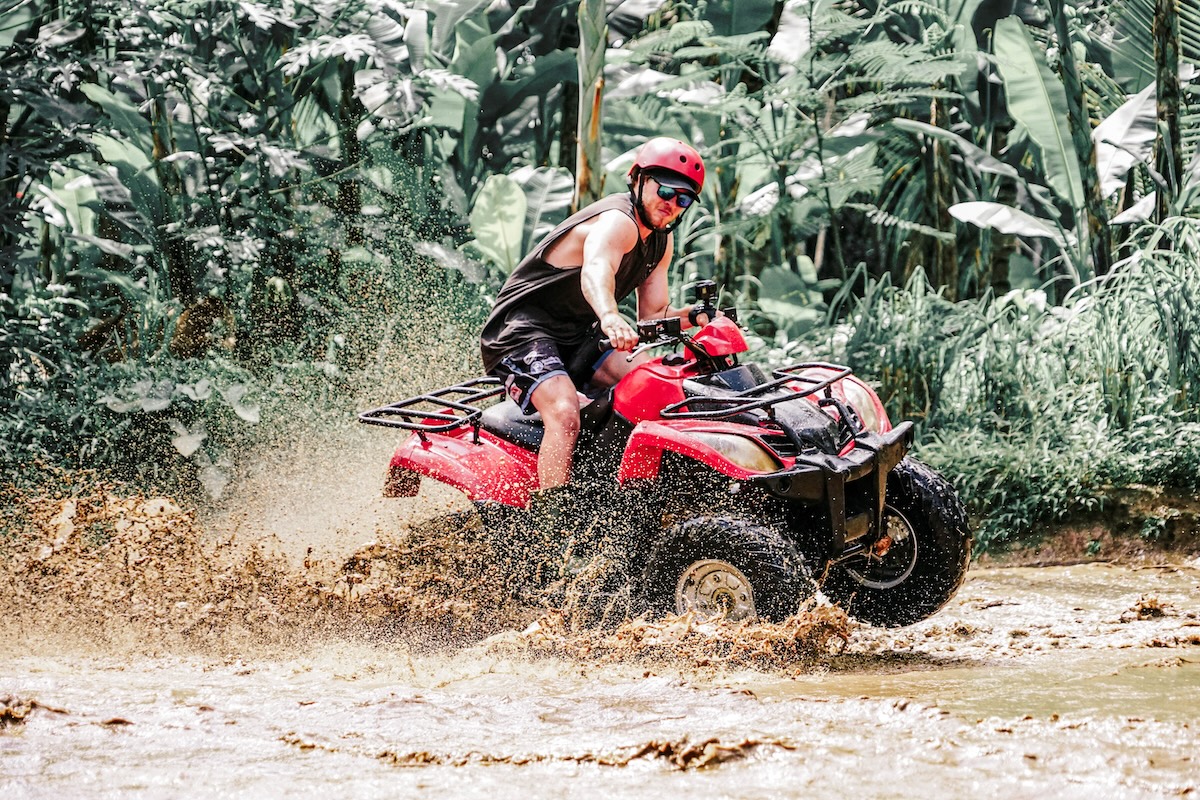Rider splashing a quad bike through the muddy river track on the Ubud ATV ride