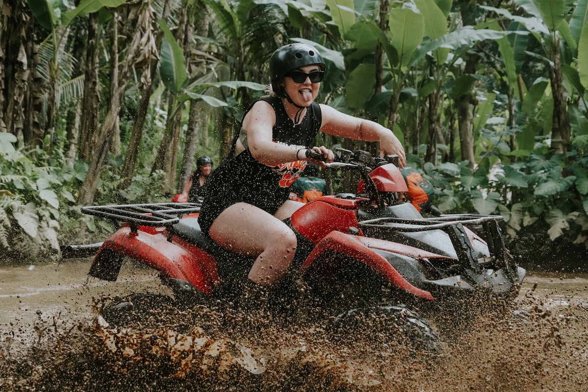 Rider splashing mud on an ATV quad bike through the jungle track in Ubud