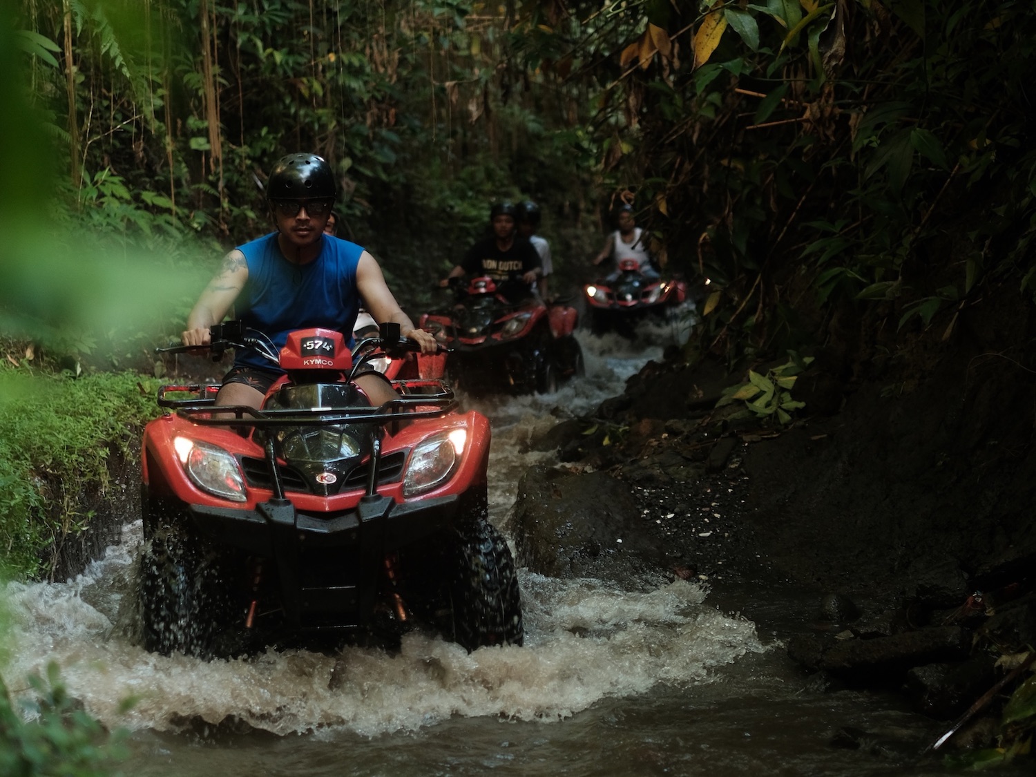 Convoy of ATV quad bikes riding down the jungle river track in Ubud